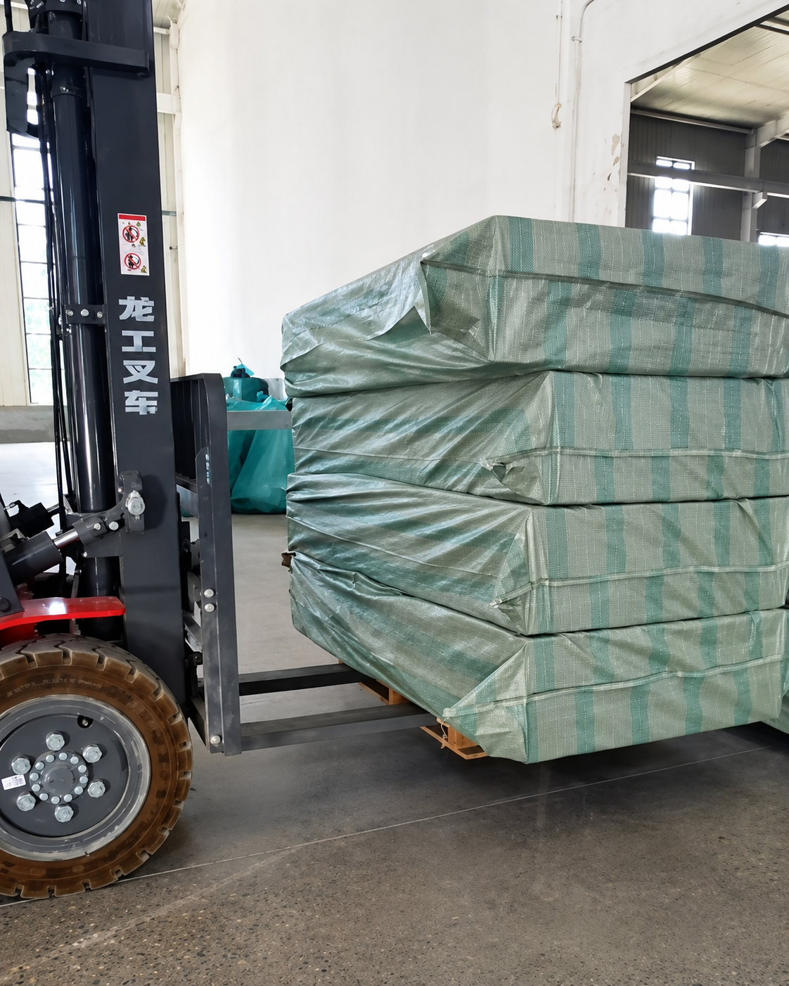 Factory forklift loading high-density wrapped pallets of electric ICU hospital beds in warehouse