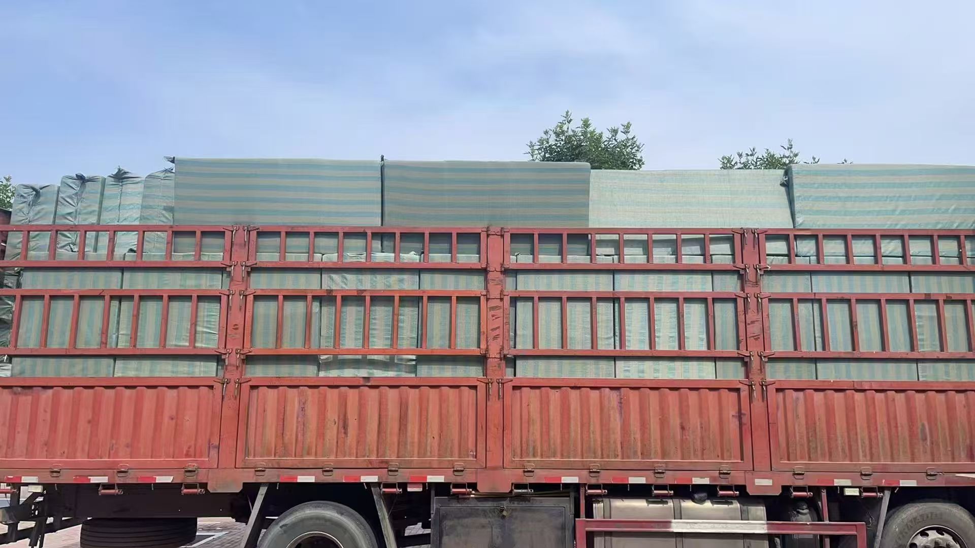 Full flatbed transport truck loaded with wrapped export pallets of mobility aids bound for container port